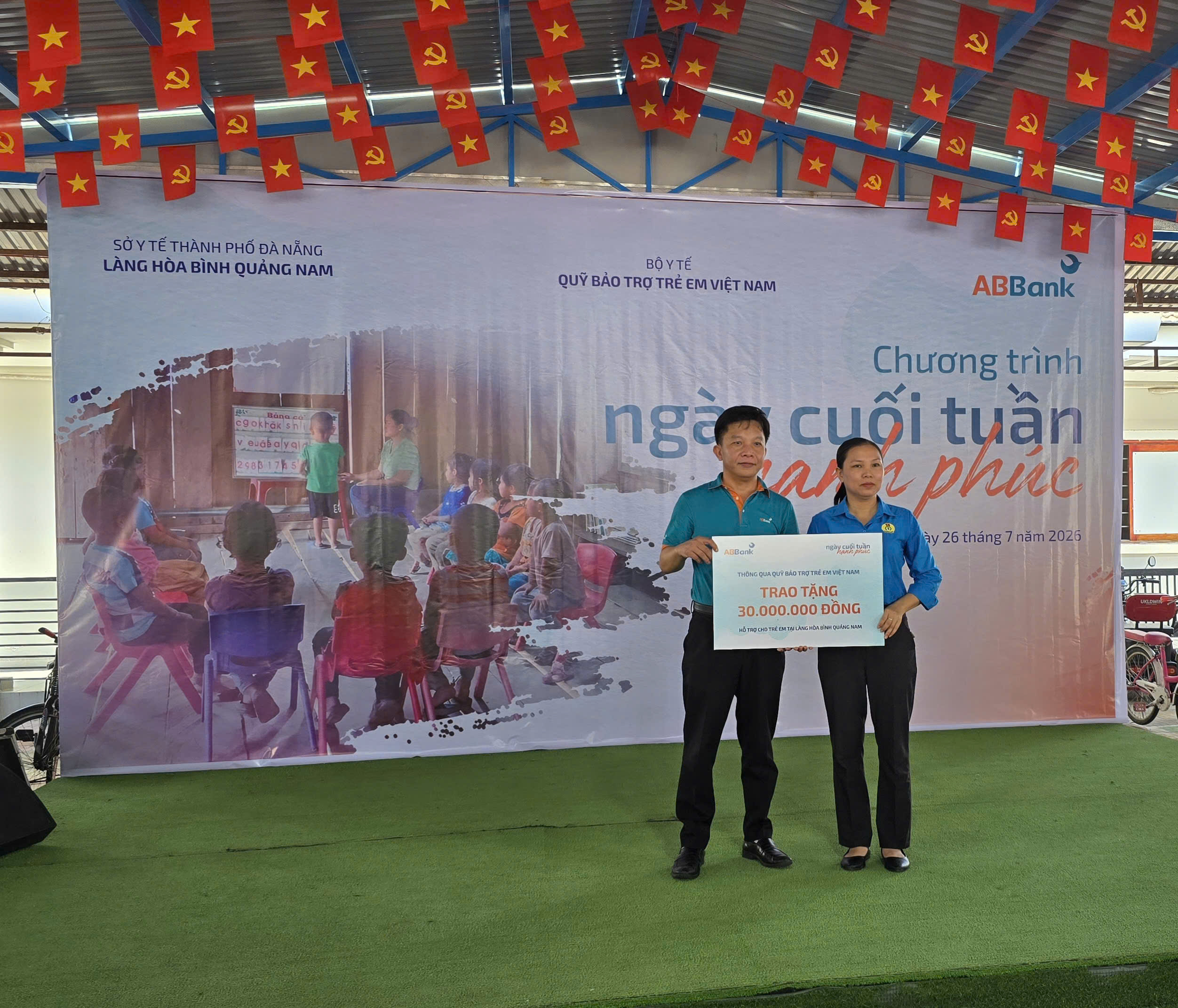 Đại diện Ngân hàng ABBank trao biểu trưng tài trợ 30 triệu đồng cho Làng Hòa Bình Quảng Nam; đại diện lãnh đạo Làng tiếp nhận